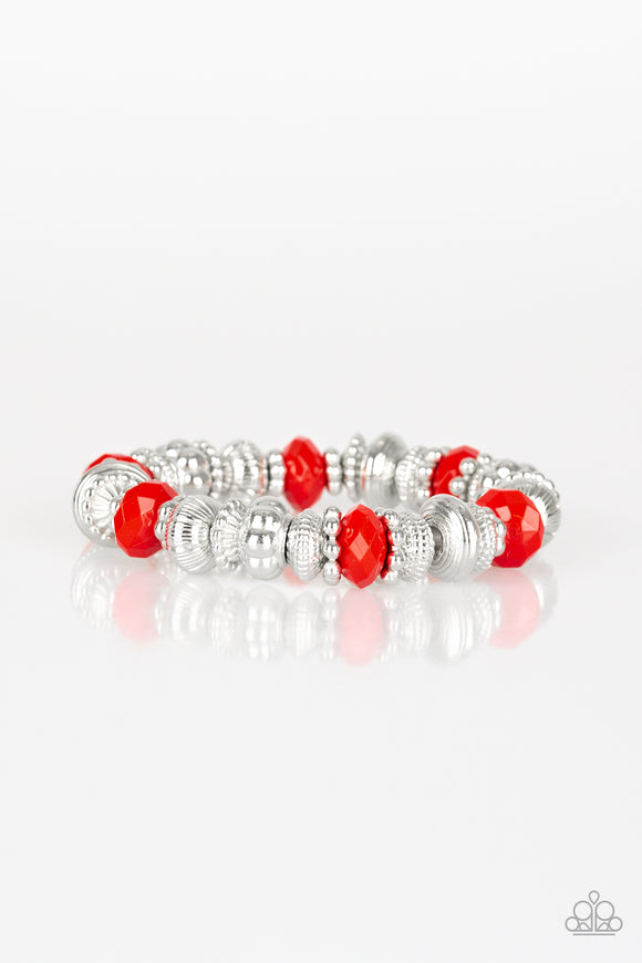 A collection of faceted red beads, ornate silver beads, and studded silver rings are threaded along a stretchy band around the wrist for a colorfully refined look.