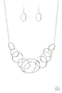 Featuring a subtle hammered finish, a collection of asymmetrical silver rings join into a stationary pendant below the collar for a bold look. Features an adjustable clasp closure.