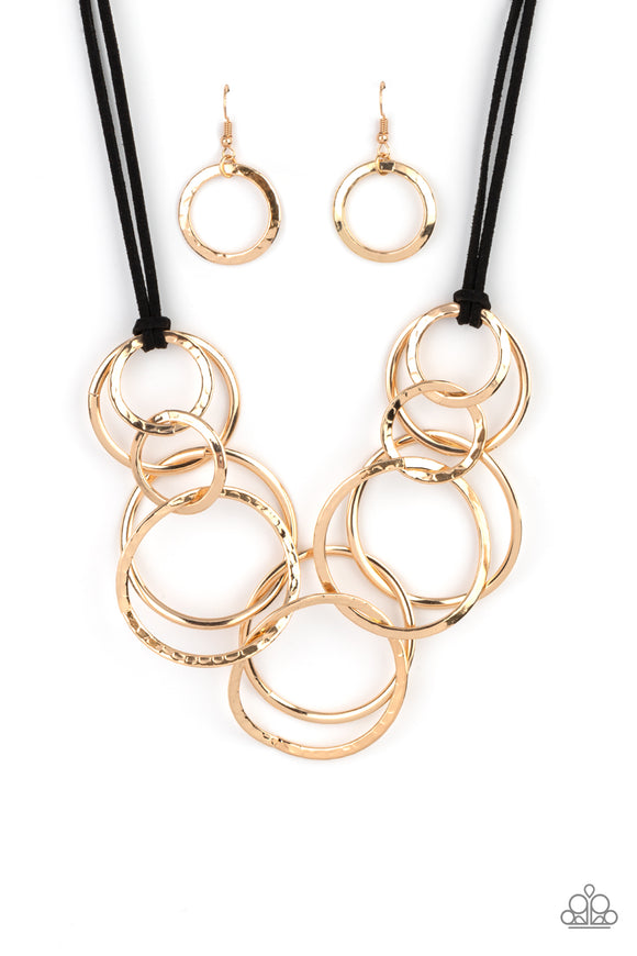 Black suede cords knot around a mismatched assortment of hammered gold rings that interlock below the collar, creating two rows of dizzying texture. Features an adjustable clasp closure. Sold as one individual necklace. Includes one pair of matching earrin