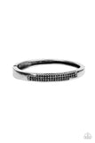 The front of a silver frame is chiseled away, revealing two rows of glitzy black rhinestones across the center of a gritty bangle-like bracelet. Features a hinged closure.