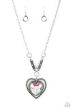 Bordered in spun silver ribbons, an oversized iridescent heart gem is pressed into a silver heart frame below the collar. The flirtatious pendant attaches to silver rings and decorative silver frames dotted in matching iridescent rhinestones, resulting in a dash of vintage inspired romance. Due to its prismatic palette, color may vary. Features an adjustable clasp closure.