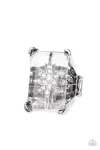 A white rhinestone dotted star twinkles behind a glassy pane that seemingly floats atop the pronged frame, resulting in a stellar statement piece. Features a stretchy band for a flexible fit.