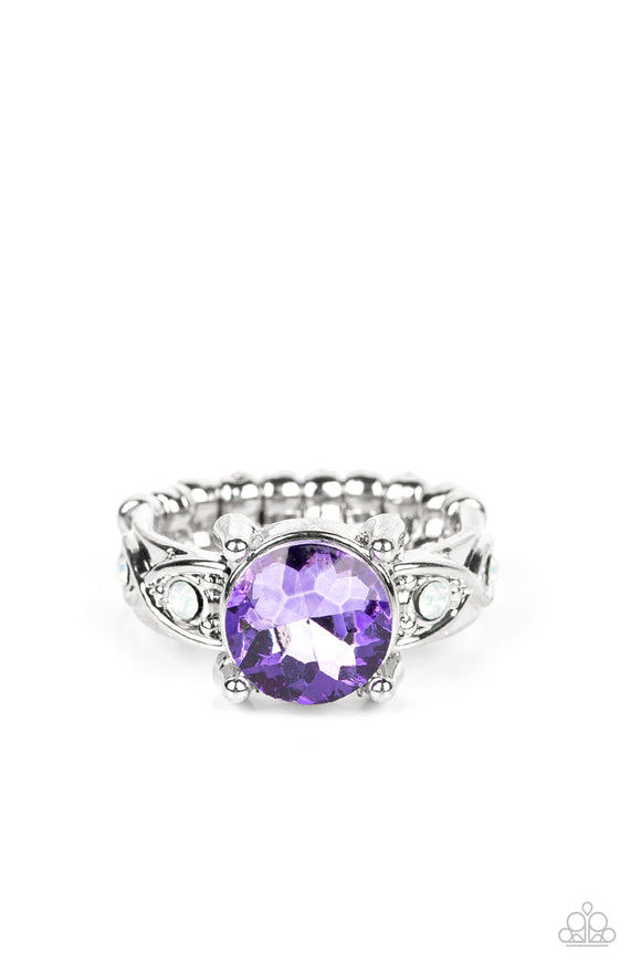 An oversized purple gem is nestled between silver prongs atop a band swirling with silver ribbons and dotted with dainty opal rhinestones, resulting in a stellar sparkle atop the finger. Features a dainty stretchy band for a flexible fit.