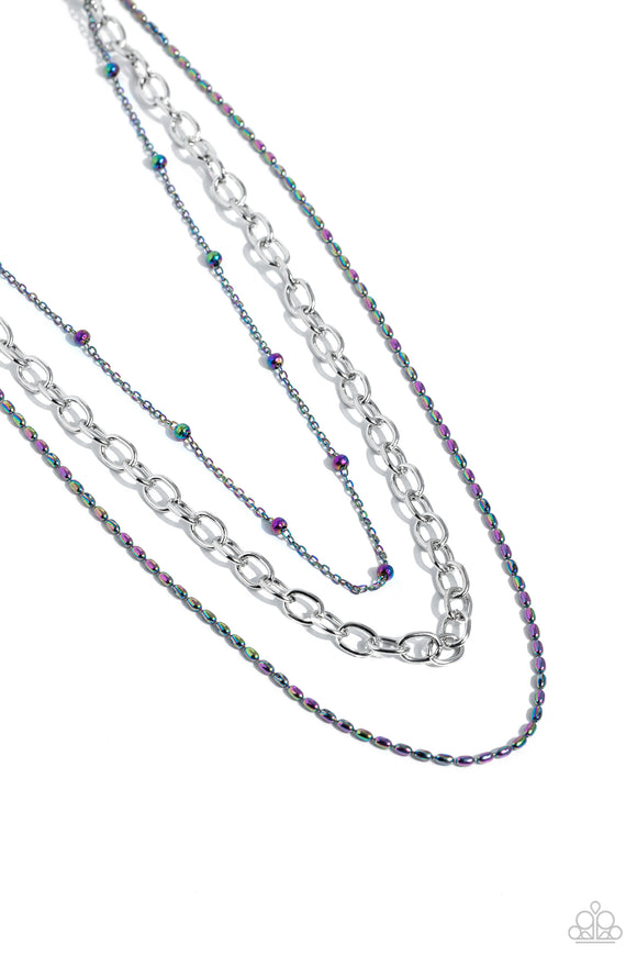 A sleek silver link chain swings from the middle of a display of mismatched dainty oil spill chains, creating an edgy layered display. Features an adjustable clasp closure.  Sold as one individual necklace. Includes one pair of matching earrings
