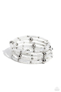 Pearly white seed beads, and various-sized silver accents are threaded along a coiled wire, creating a refined infinity wrap-style bracelet around the wrist.