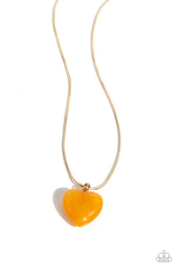 Brushed in a glittery finish, a golden heart dangles at the bottom of a lengthened gold snake chain, creating a glittery pendant. Features an adjustable clasp closure.