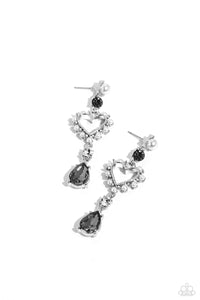 A white pearl and green gem are pronged in silver fittings as they give way to an airy heart frame embellished with dainty white pearls and iridescent rhinestones for a dreamy finish. A white gem and smoky teardrop gem, pressed in the same pronged fittings, dramatically swing from the bottom of the airy heart frame, capturing and reflecting light at every hypnotic sway. Earring attaches to a standard post fitting. Due to its prismatic palette, color may vary.
